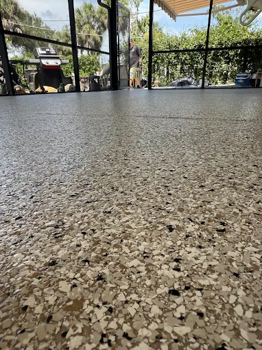 Decorative epoxy floor coating on a screened patio in Palmetto, FL with a durable flake finish for long-lasting protection.